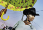 Ceres, South Africa, 2006. A woman wearing a white mud face mask and cowboy hat, walks through her neighbourhood.